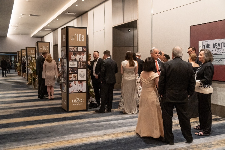 Attendees look at pillars depicting photos from each decade of the medical school